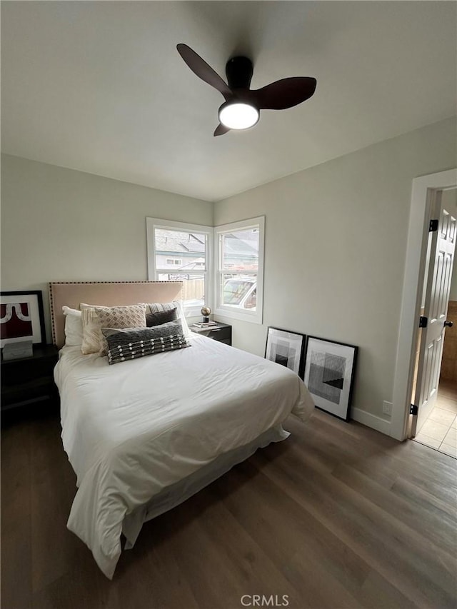 bedroom featuring ceiling fan, baseboards, and wood finished floors