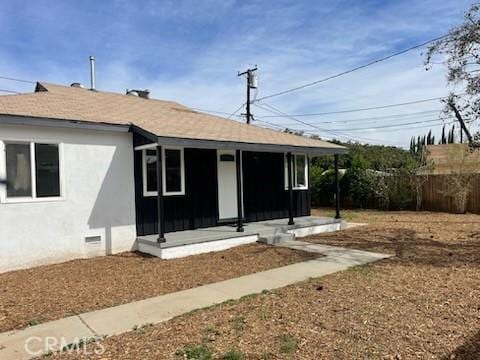 back of house featuring crawl space, roof with shingles, fence, and stucco siding