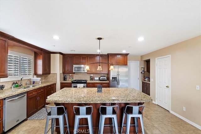 kitchen with a breakfast bar area, stainless steel appliances, a kitchen island, a sink, and backsplash