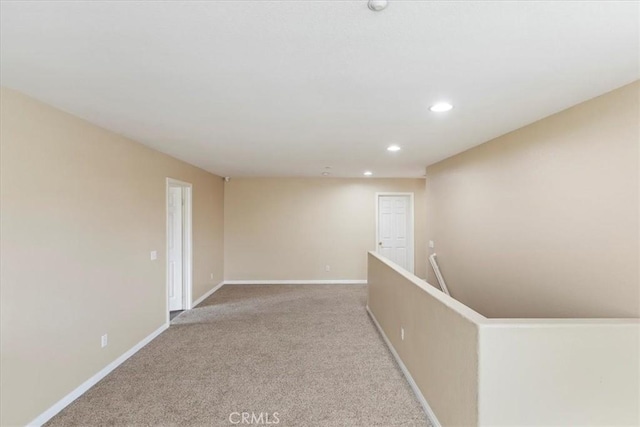 empty room featuring recessed lighting, baseboards, and light colored carpet