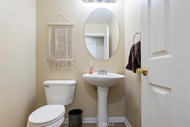 bathroom with a sink, toilet, and baseboards