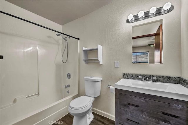 bathroom with toilet, tub / shower combination, vanity, wood finished floors, and baseboards