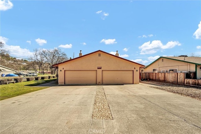 view of side of home featuring a garage, fence, and stucco siding