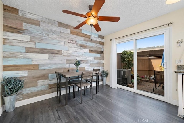 dining room featuring wooden walls, an accent wall, a textured ceiling, and wood finished floors