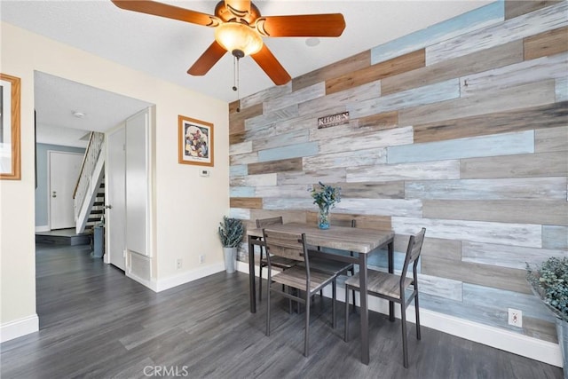 dining space featuring wooden walls, visible vents, an accent wall, wood finished floors, and stairs