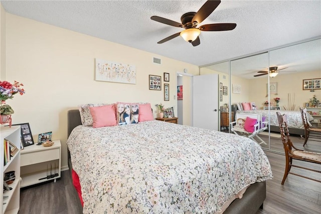 bedroom with a closet, a textured ceiling, visible vents, and wood finished floors