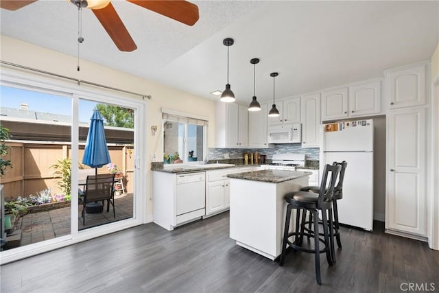 kitchen featuring a center island, tasteful backsplash, white cabinetry, white appliances, and a kitchen breakfast bar