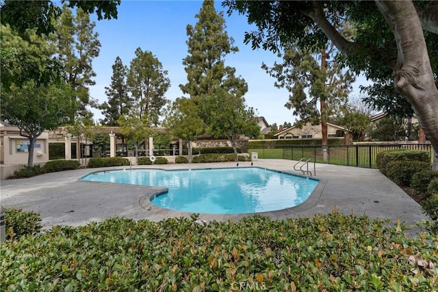 community pool with a patio area and fence