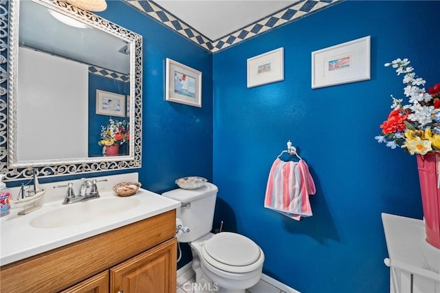 half bathroom with vanity, toilet, and baseboards