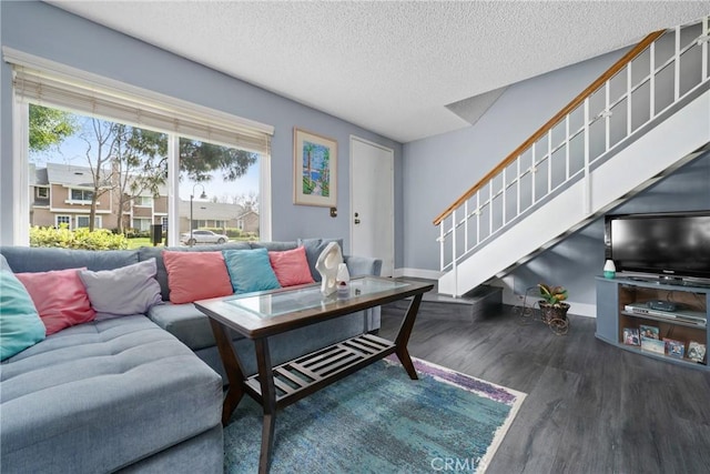 living area featuring baseboards, stairway, a textured ceiling, and wood finished floors