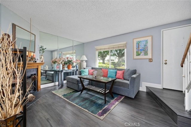 living area featuring dark wood finished floors, a textured ceiling, baseboards, and stairs