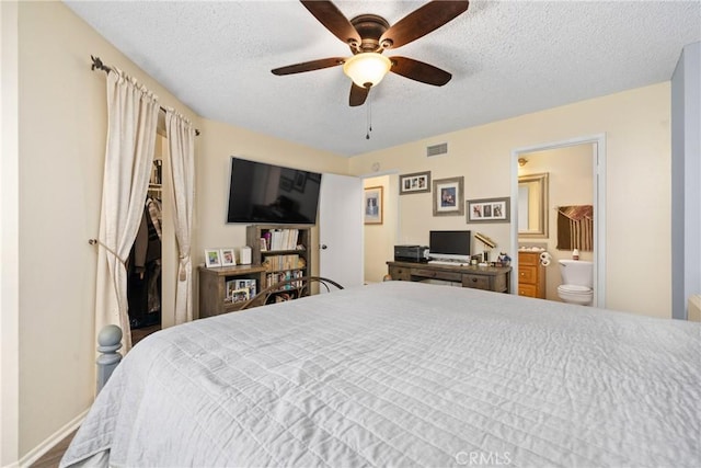 bedroom featuring visible vents, a ceiling fan, a textured ceiling, ensuite bath, and baseboards