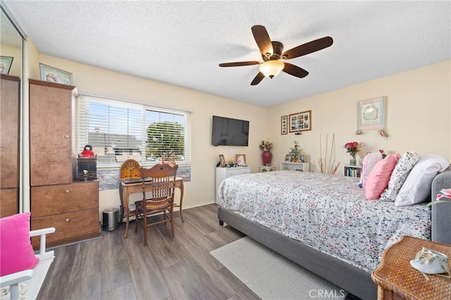 bedroom featuring a textured ceiling, ceiling fan, wood finished floors, and baseboards