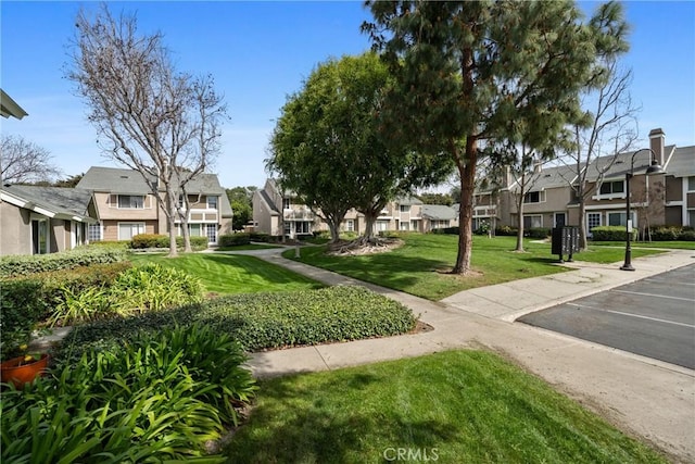 surrounding community featuring uncovered parking, a lawn, and a residential view