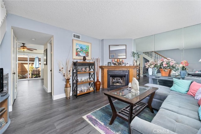 living area featuring a fireplace, wood finished floors, visible vents, baseboards, and stairway