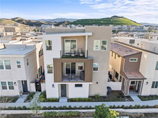 view of front of house with a balcony, a residential view, a mountain view, and stucco siding