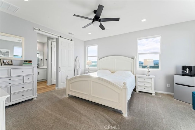 bedroom featuring light carpet, a barn door, and visible vents