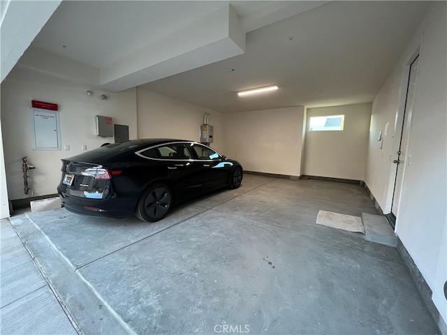 garage featuring electric panel, water heater, and baseboards