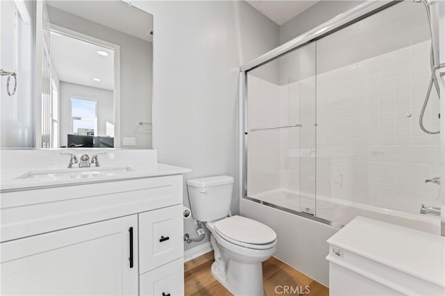 full bathroom with toilet, enclosed tub / shower combo, wood finished floors, and vanity