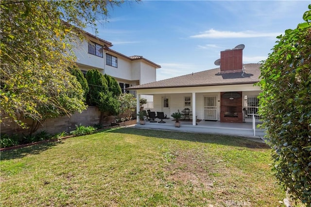 rear view of house with a lawn, a patio area, and fence