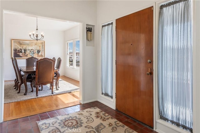 entryway featuring a chandelier, dark tile patterned flooring, and baseboards