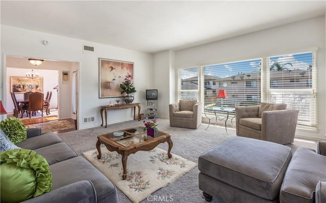 living area with a chandelier, carpet floors, and visible vents