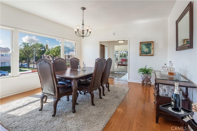 dining room with wood-type flooring, a notable chandelier, and baseboards