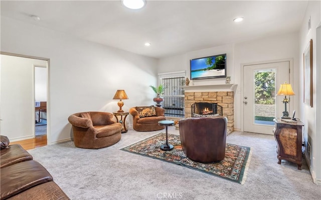 carpeted living area featuring recessed lighting, a stone fireplace, and baseboards