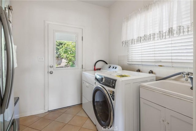 clothes washing area with washing machine and dryer, laundry area, a sink, and light tile patterned floors