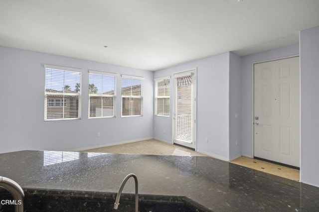 kitchen featuring baseboards and dark stone counters