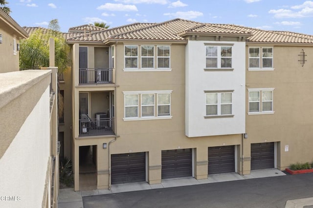 exterior space with an attached garage, a tiled roof, and stucco siding