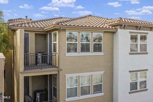 view of home's exterior featuring a tiled roof, cooling unit, a balcony, and stucco siding