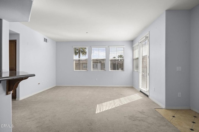 unfurnished living room featuring carpet, visible vents, and baseboards