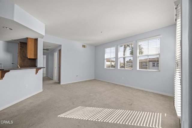 unfurnished living room featuring light carpet, visible vents, and baseboards