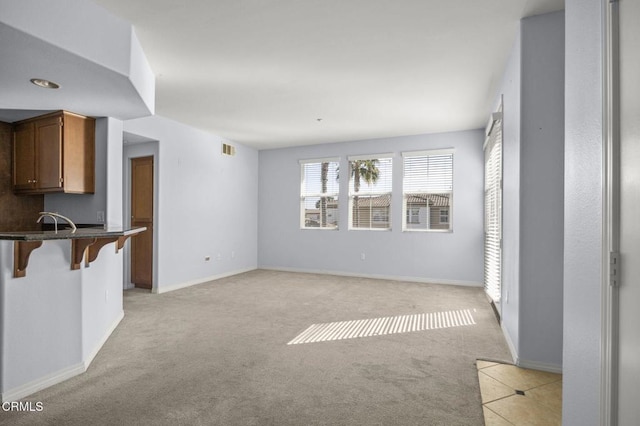 unfurnished living room with light carpet, visible vents, and baseboards