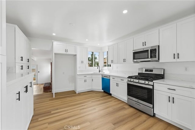 kitchen with light wood-style flooring, recessed lighting, stainless steel appliances, a sink, and white cabinets