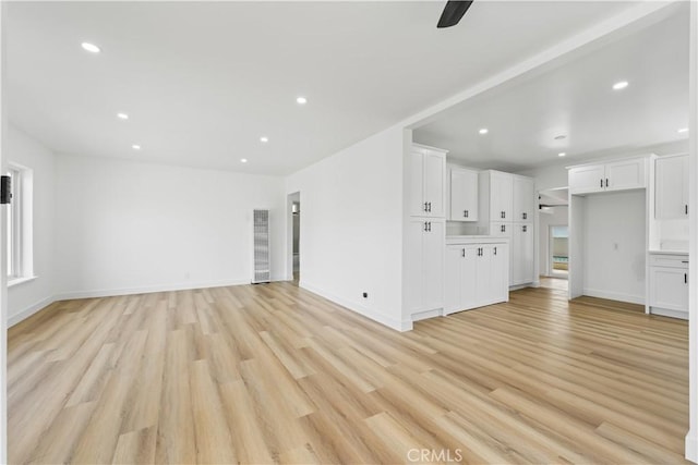 unfurnished living room with recessed lighting, light wood-style flooring, and baseboards