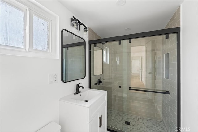 bathroom with toilet, vanity, and a shower stall