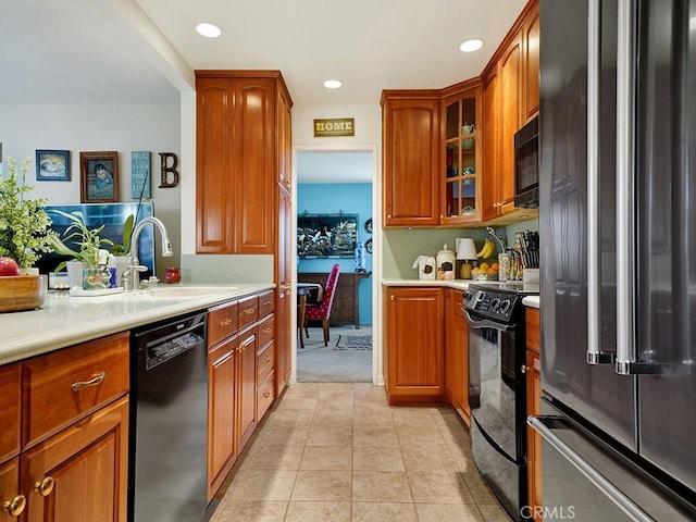 kitchen featuring black appliances, light tile patterned flooring, a sink, and light countertops