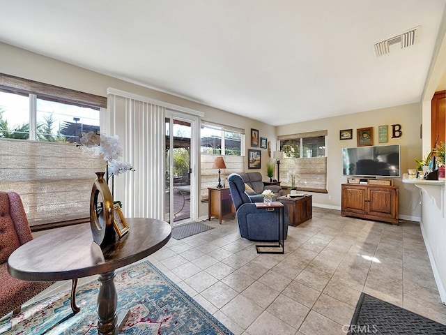 living room featuring light tile patterned floors, plenty of natural light, visible vents, and baseboards