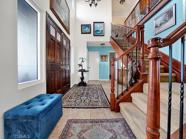 tiled foyer entrance with baseboards, stairway, and a high ceiling