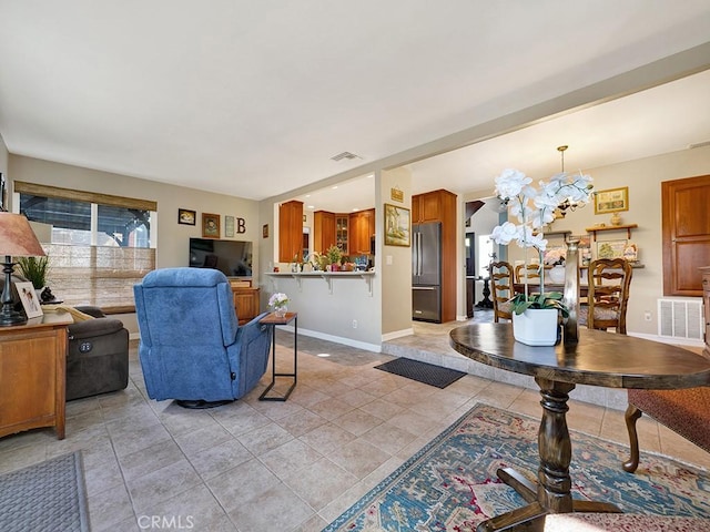 living room featuring an inviting chandelier, baseboards, visible vents, and light tile patterned flooring