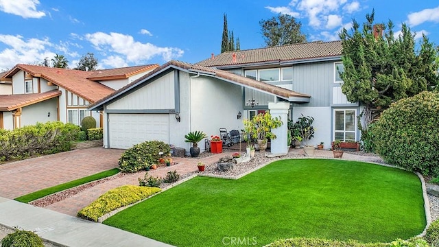 view of front of house featuring a garage, a tiled roof, a front lawn, and decorative driveway