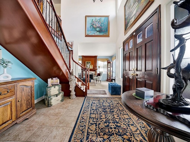 entryway with a towering ceiling, light tile patterned floors, and stairs