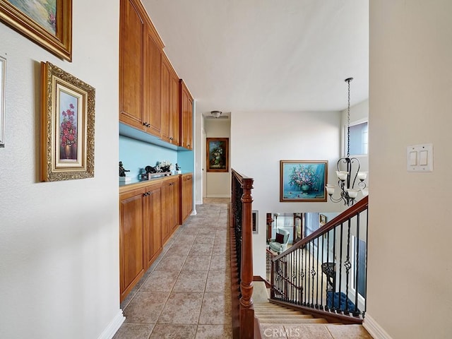 corridor featuring a chandelier, light tile patterned flooring, an upstairs landing, and baseboards