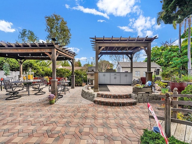 view of patio / terrace featuring an outbuilding, an outdoor kitchen, a pergola, and outdoor dining space