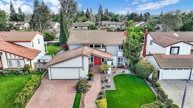 view of front of house featuring decorative driveway, a garage, a residential view, a tiled roof, and a front lawn