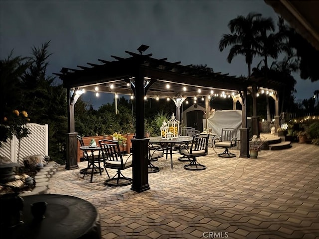 patio at night with outdoor dining area and a pergola