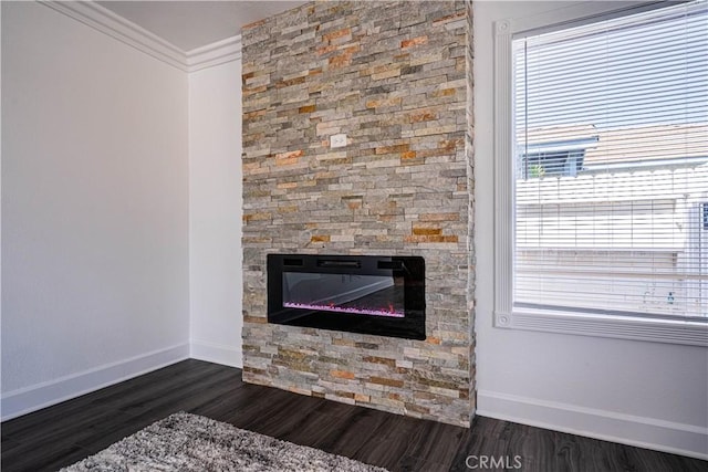 room details featuring a fireplace, baseboards, crown molding, and wood finished floors