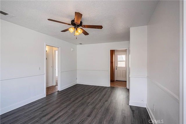 empty room with dark wood-style floors, baseboards, visible vents, and a textured ceiling